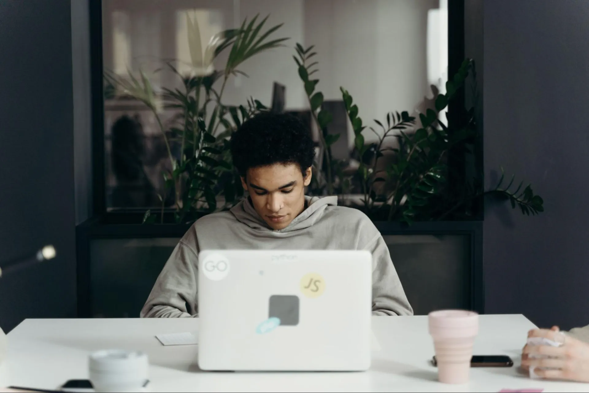 Student developer working on a laptop, testing a mobile app backend from a shared campus space